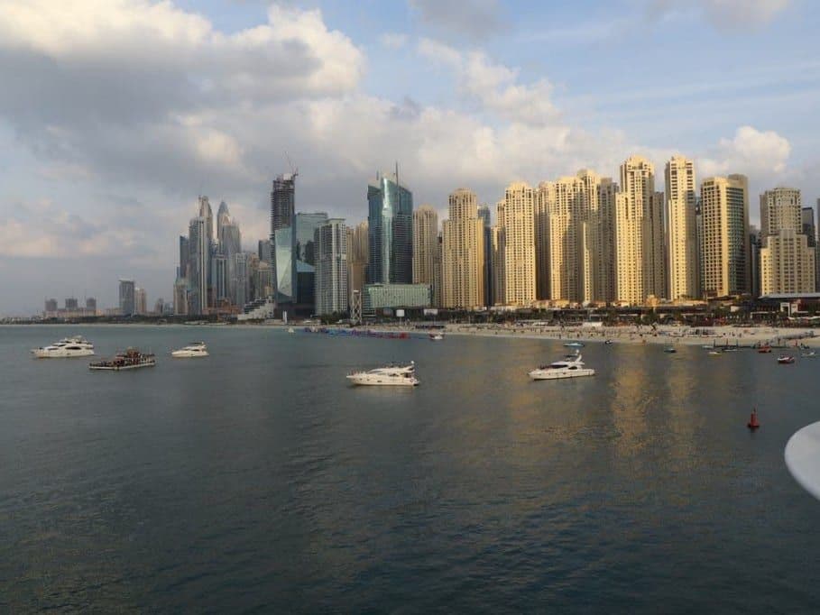 Dubai Marina towers across the water, with boats and a beach